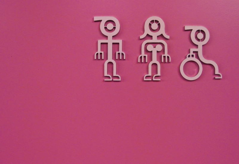 Pink icons of a man, woman and person in a wheelchair on a simple pink background.